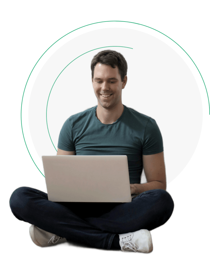 loanspot A man is sitting on the floor, smiling while using a laptop computer to get loan